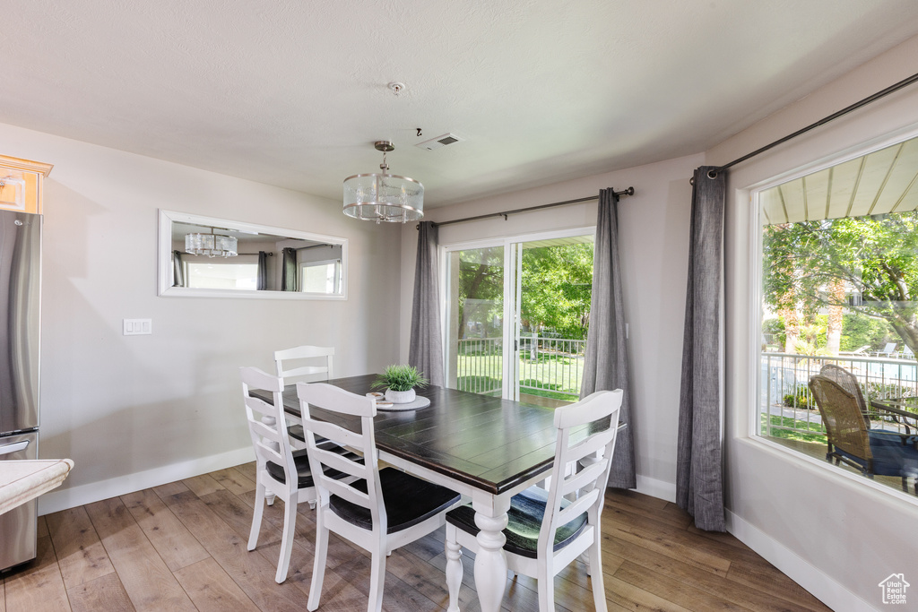 Dining room with baseboards, visible vents, a notable chandelier, and light wood-type flooring