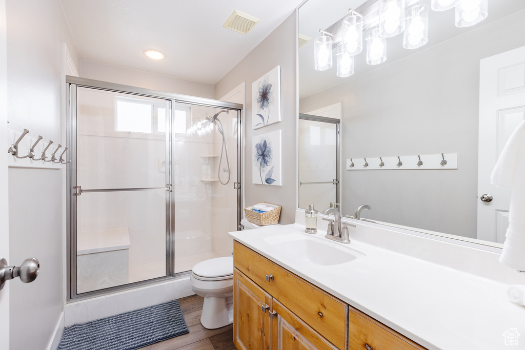 Full bathroom featuring vanity, toilet, wood finished floors, visible vents, and a stall shower