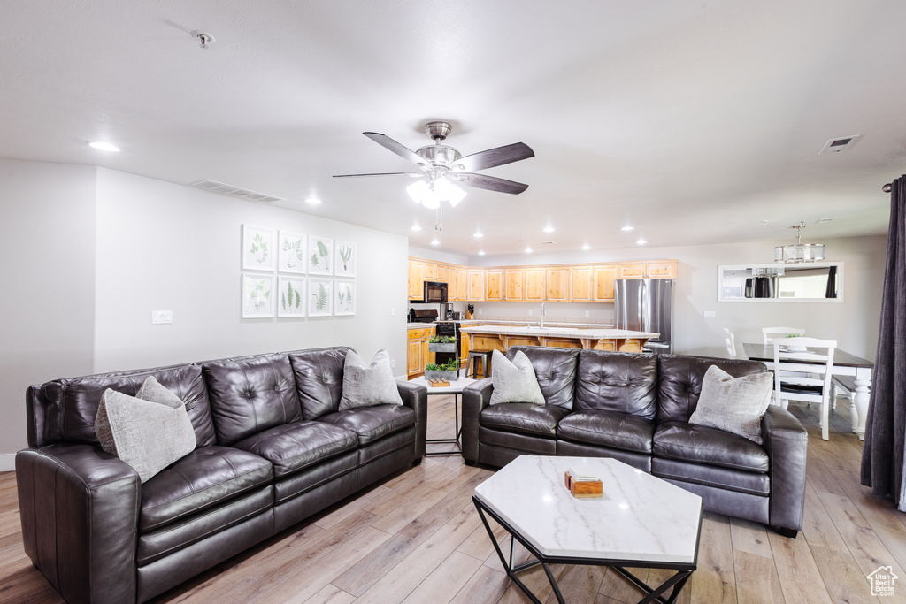 Living room featuring recessed lighting, ceiling fan with notable chandelier, and light wood-type flooring