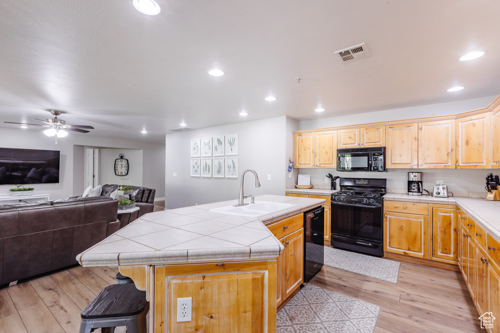 Kitchen with tile countertops, recessed lighting, a sink, and black appliances