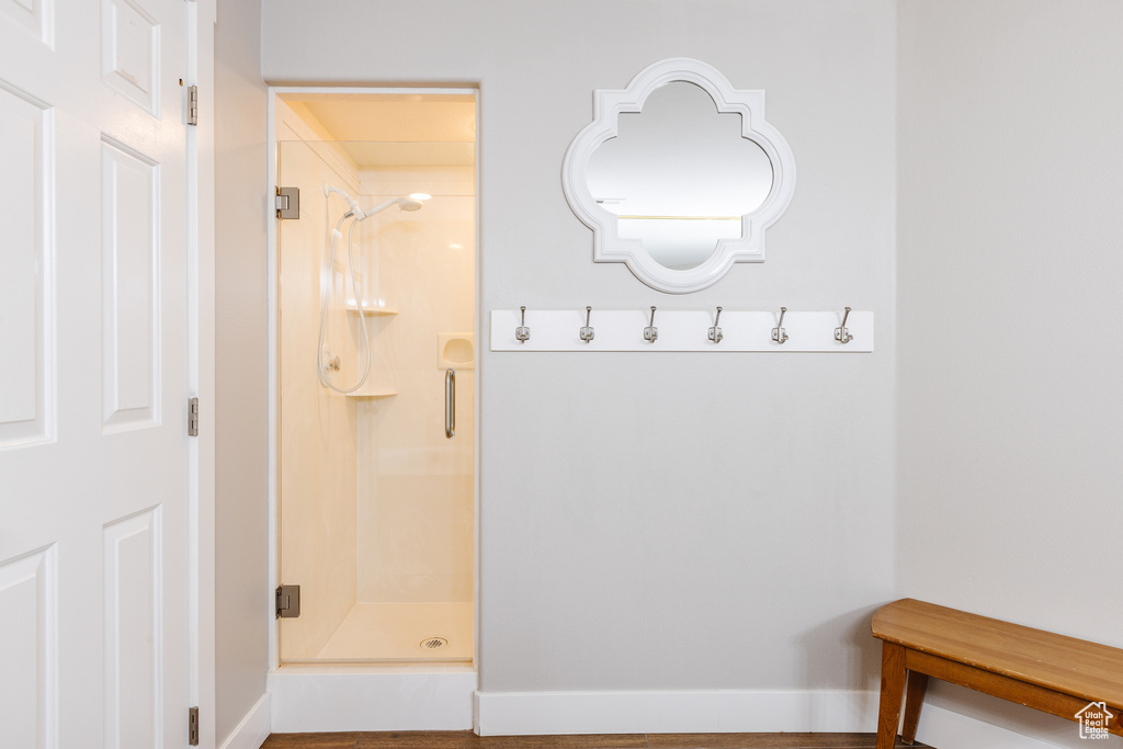 Full bath featuring baseboards, a stall shower, and wood finished floors