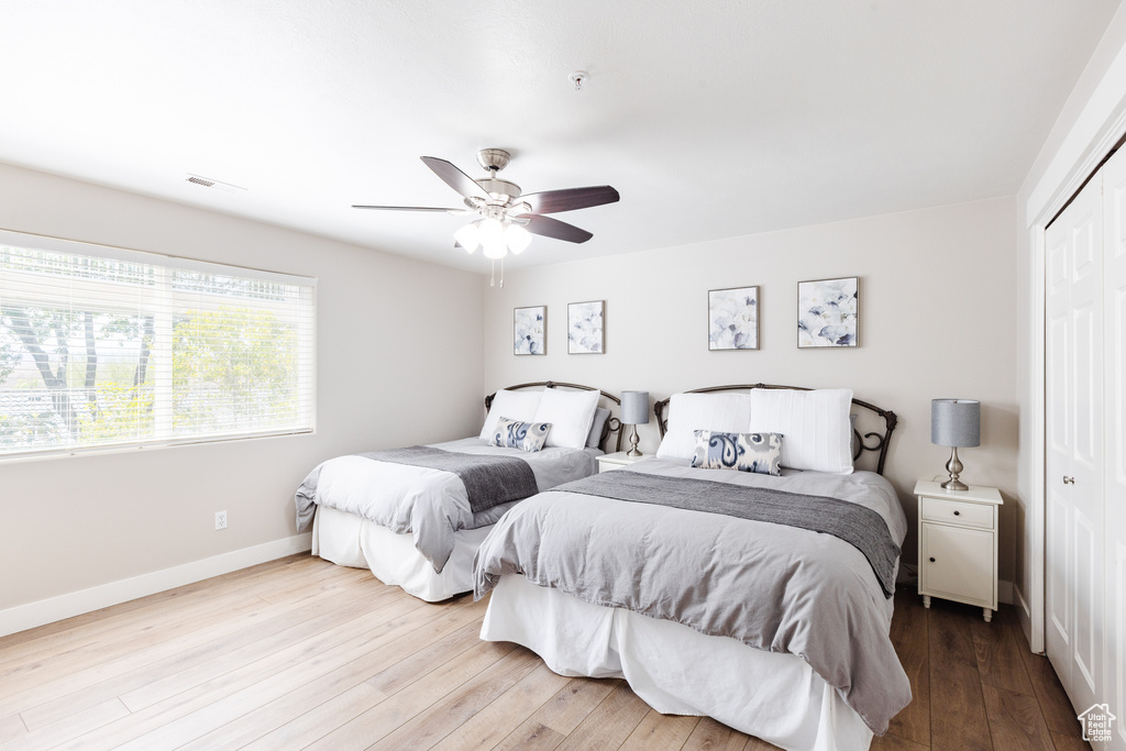 Bedroom featuring ceiling fan, baseboards, wood finished floors, visible vents, and a closet