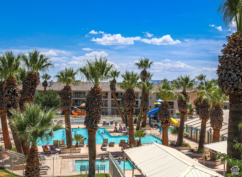 Pool with a patio, a water slide, playground community, and fence