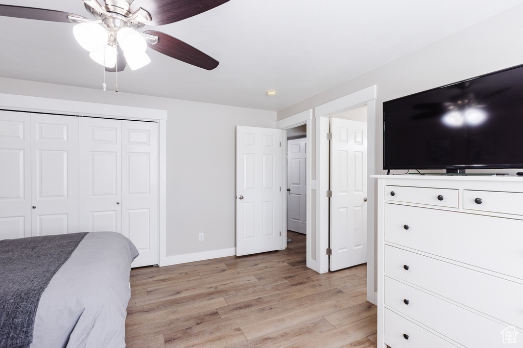 Bedroom featuring baseboards, a ceiling fan, a closet, and light wood-style flooring