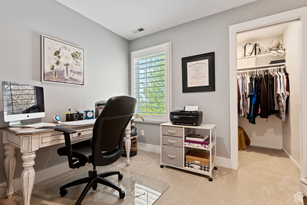 Home office with baseboards, visible vents, and light colored carpet