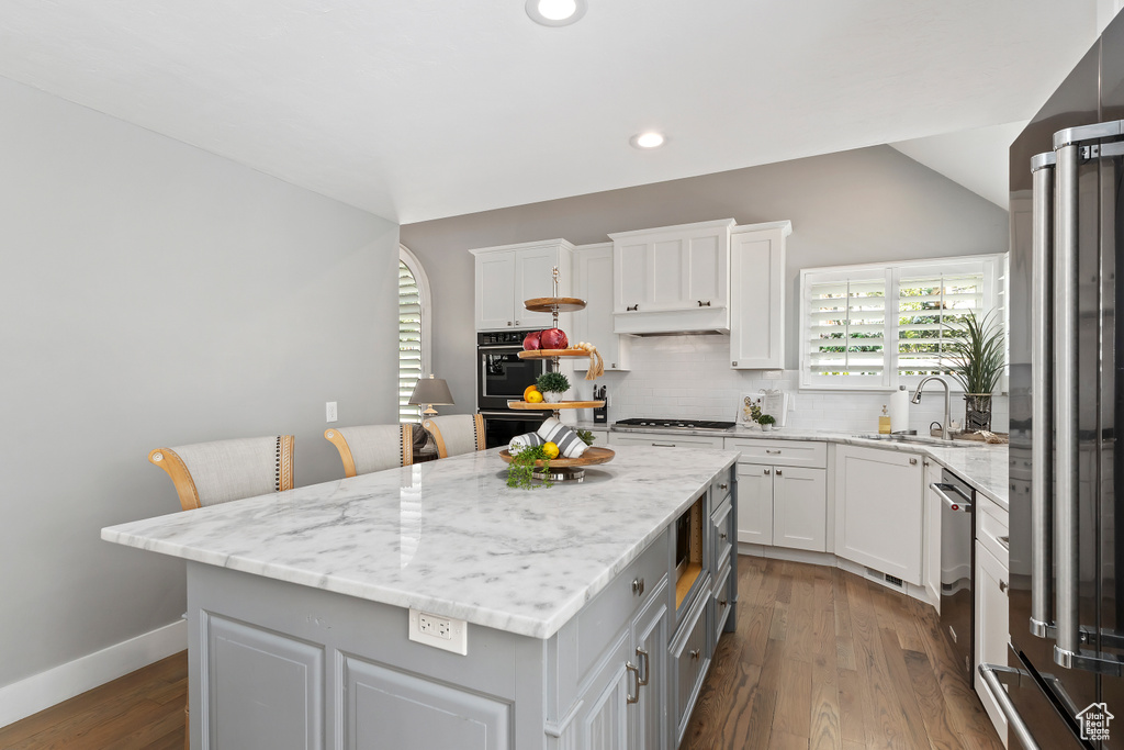 Kitchen with tasteful backsplash, appliances with stainless steel finishes, white cabinets, a sink, and a center island
