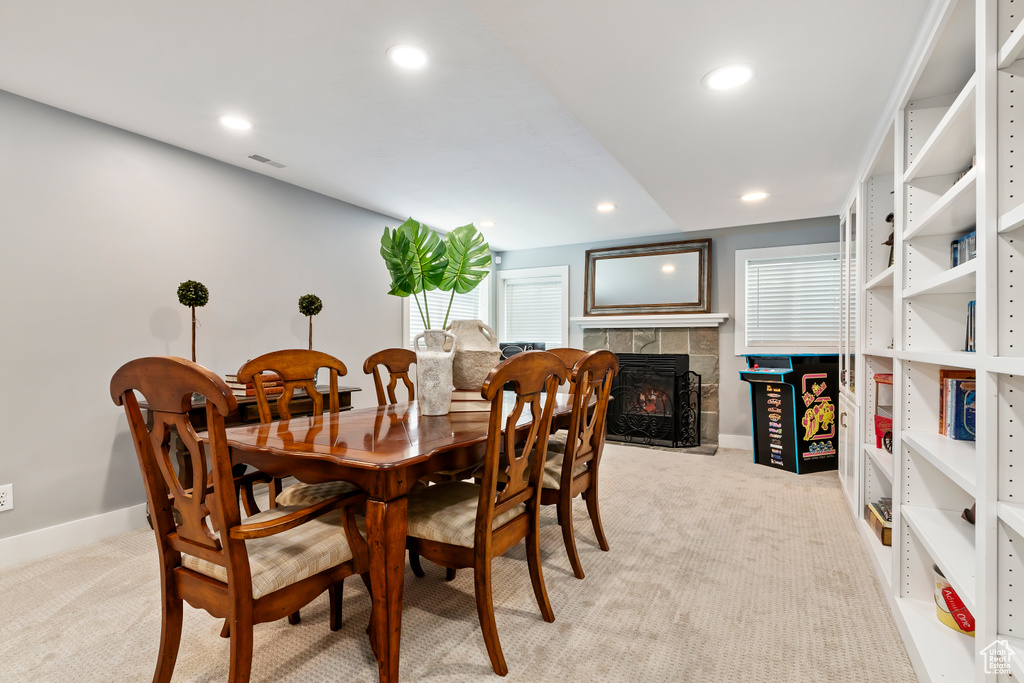 Dining room with a fireplace, baseboards, recessed lighting, and light carpet