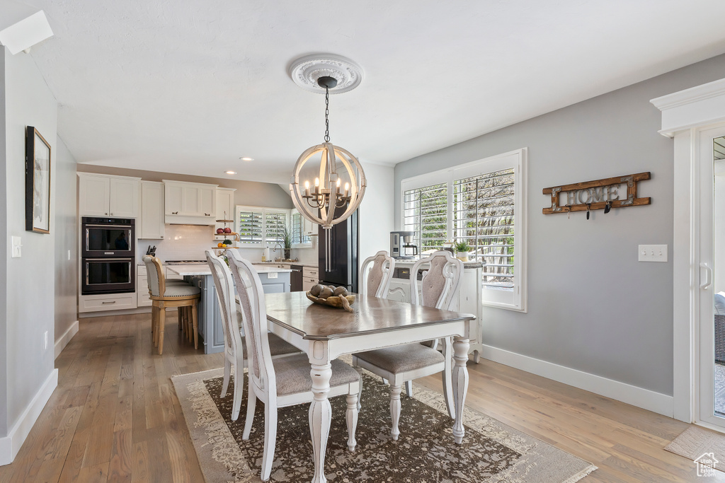 Dining room with a chandelier, light wood-type flooring, recessed lighting, and baseboards