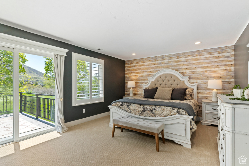 Bedroom with an accent wall, access to outside, wooden walls, and light colored carpet
