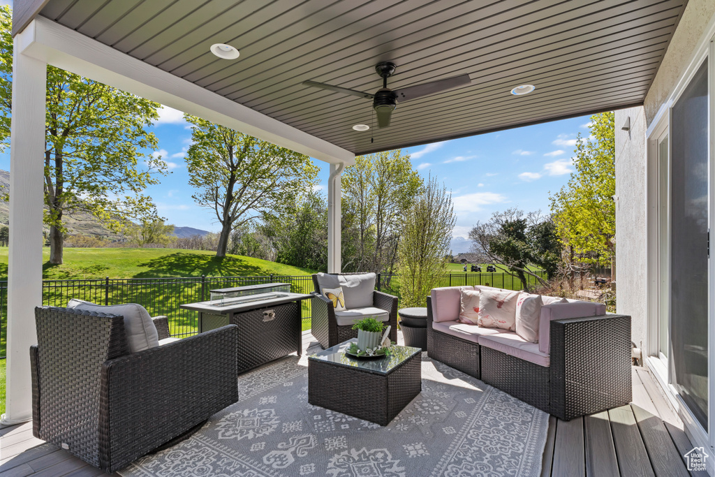 Wooden terrace featuring an outdoor hangout area, a mountain view, ceiling fan, and fence