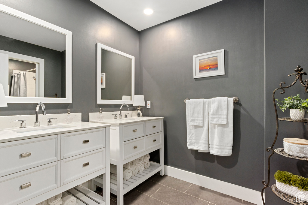 Bathroom featuring tile patterned floors, baseboards, two vanities, and a sink