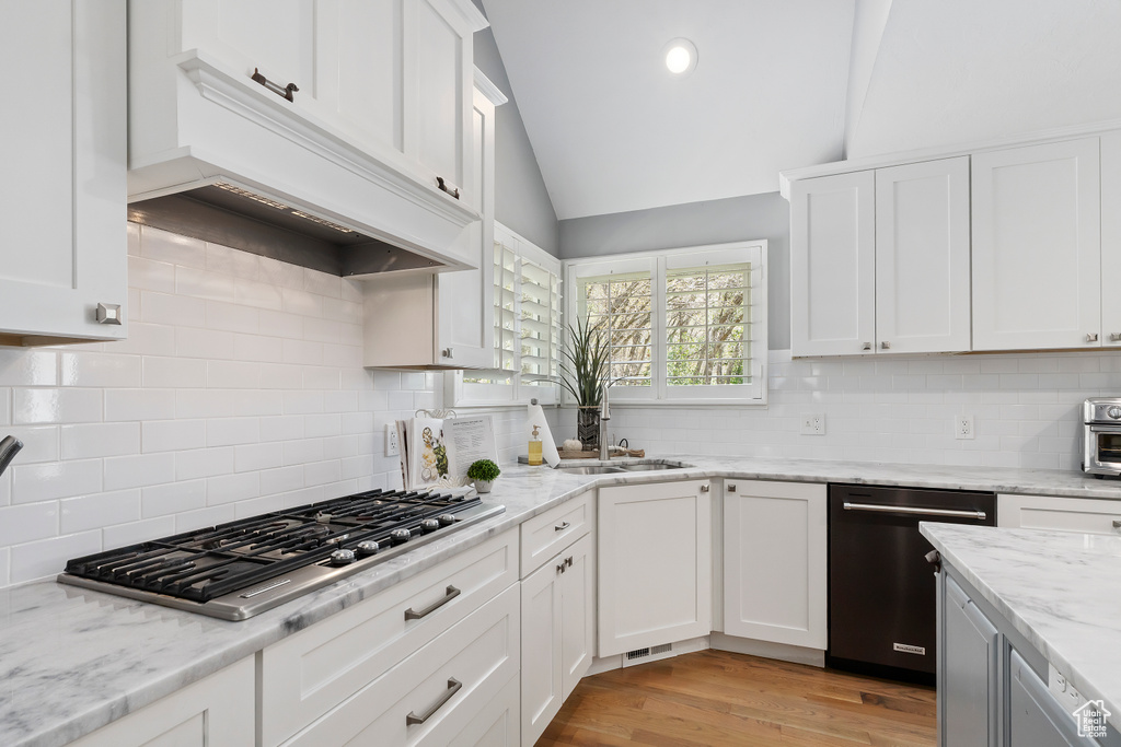Kitchen with lofted ceiling, tasteful backsplash, a sink, dishwasher, and stainless steel gas cooktop