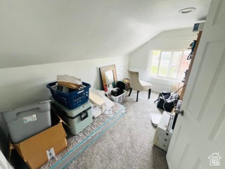 Additional living space with vaulted ceiling and carpet