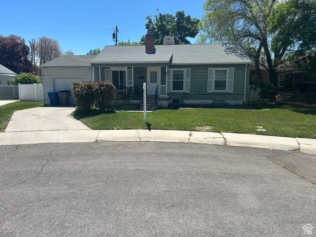 Ranch-style home with a chimney, an attached garage, concrete driveway, a porch, and a front lawn