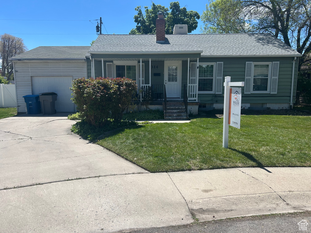 Ranch-style home with a chimney, an attached garage, concrete driveway, a front yard, and a porch