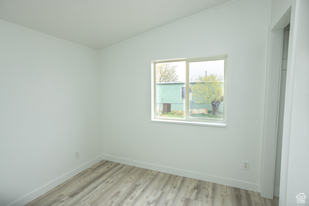 Empty room with baseboards, ornamental molding, and light wood-style flooring