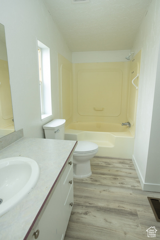 Full bath featuring vanity, toilet, wood finished floors,  shower combination, and visible vents