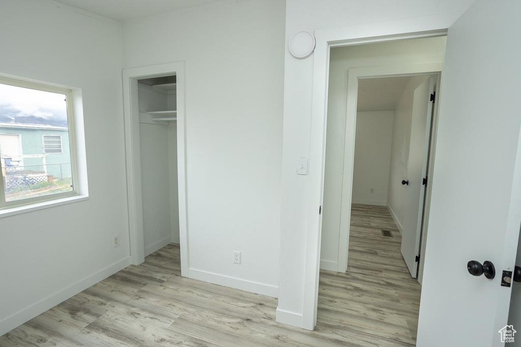 Unfurnished bedroom featuring a closet, baseboards, visible vents, and light wood-style floors