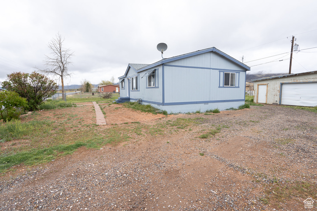 View of side of home with an outdoor structure, driveway, and crawl space
