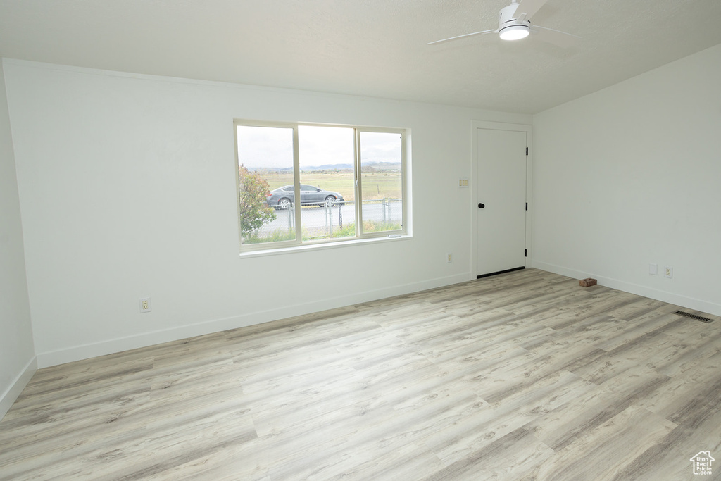 Unfurnished room featuring baseboards, a ceiling fan, light wood finished floors, and visible vents