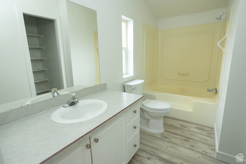 Bathroom with shower / bathtub combination, vanity, toilet, and wood finished floors