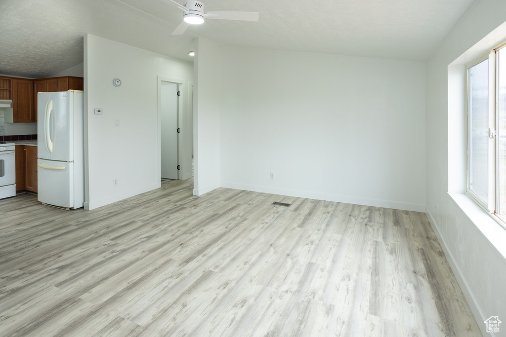 Unfurnished living room with light wood-type flooring, a ceiling fan, and baseboards