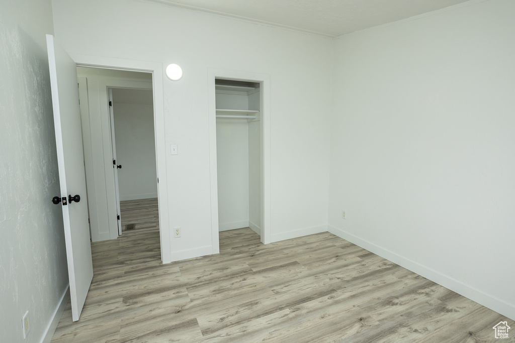 Unfurnished bedroom with baseboards, light wood-style flooring, and a closet