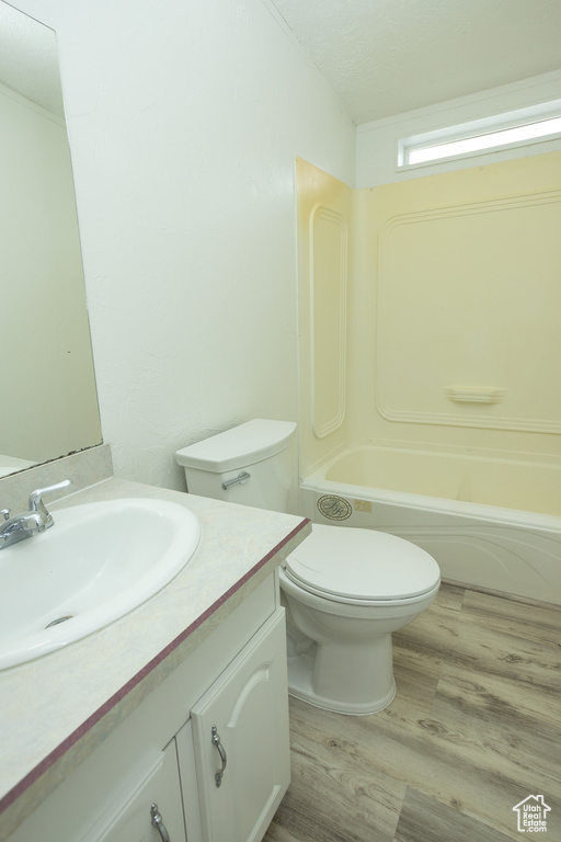 Full bath featuring vanity, toilet, wood finished floors, and shower / washtub combination