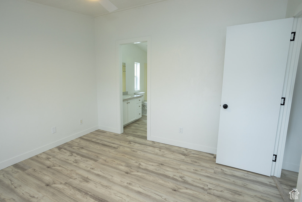 Unfurnished bedroom featuring light wood-style floors, baseboards, and ensuite bathroom