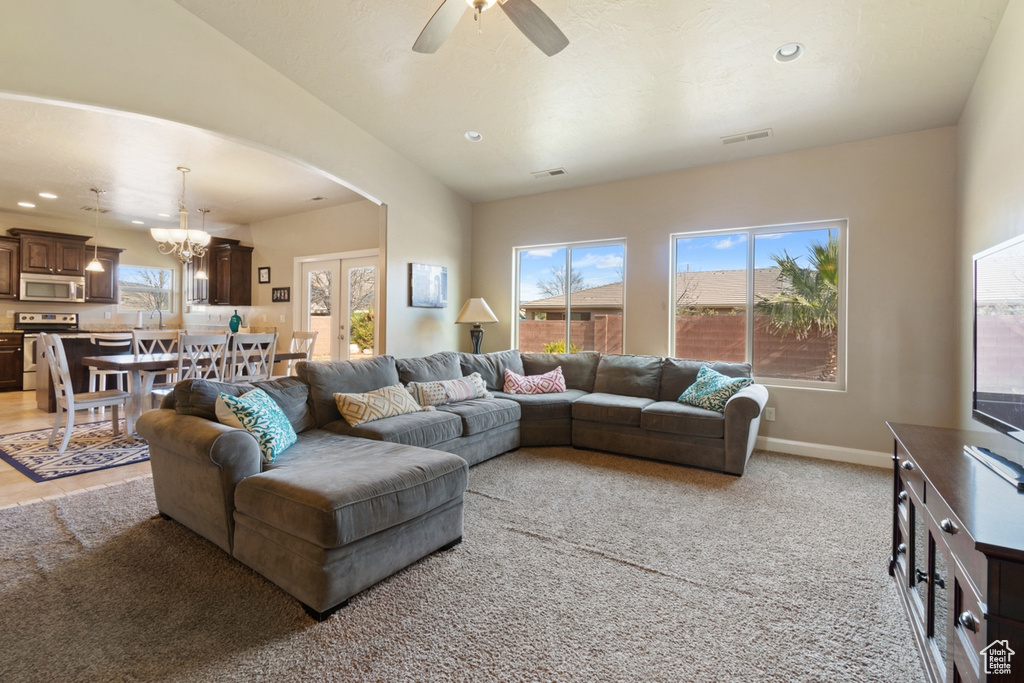 Carpeted living room featuring sink, french doors, ceiling fan with notable chandelier, and lofted ceiling