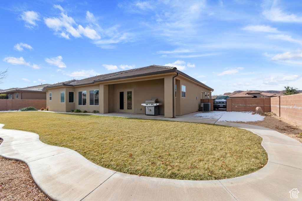 Rear view of house featuring central AC unit, a lawn, and a patio area