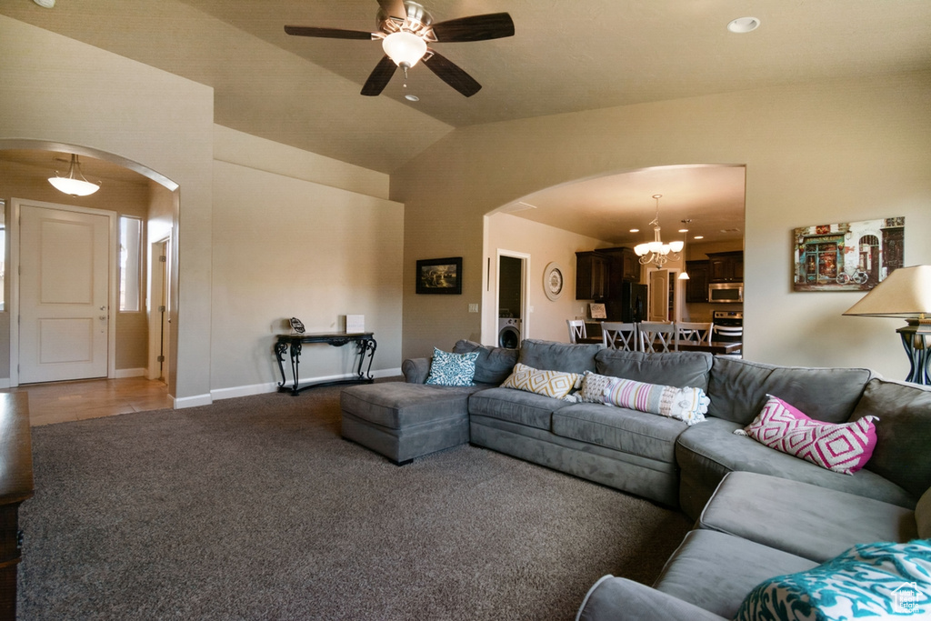 Tiled living room with washer / clothes dryer, vaulted ceiling, and ceiling fan with notable chandelier