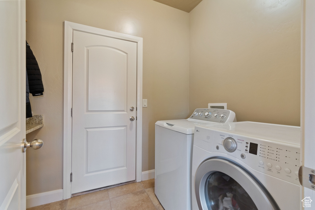 Washroom featuring washing machine and clothes dryer and light tile floors