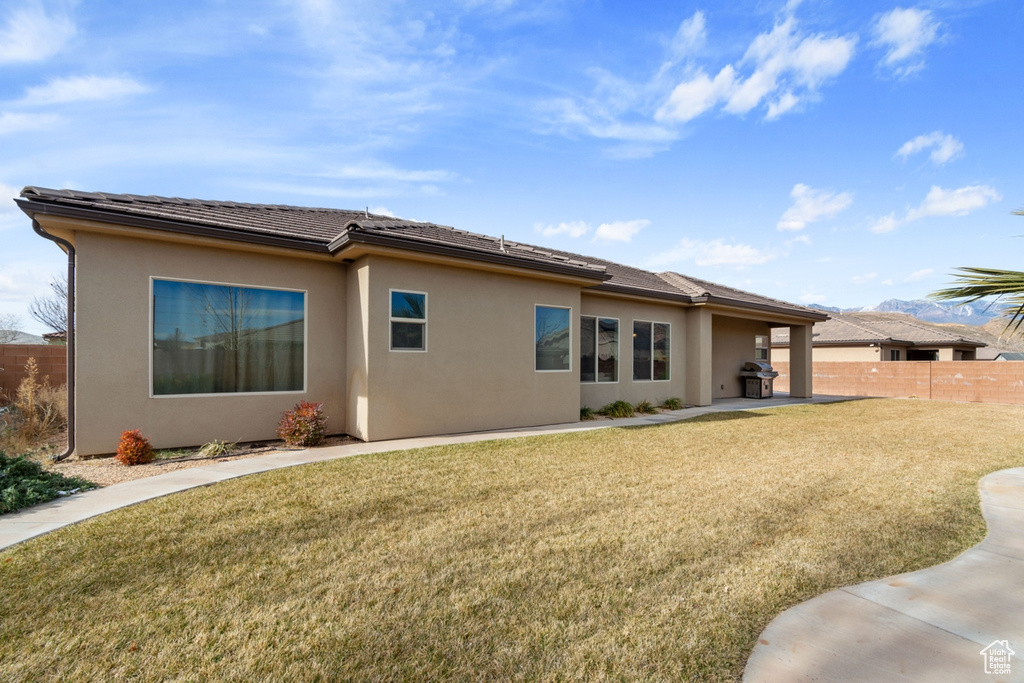 Back of house with a lawn and a patio area