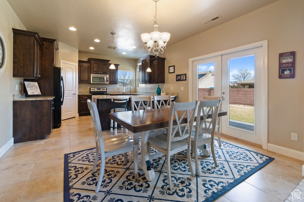 Dining space featuring french doors, light tile flooring, and an inviting chandelier