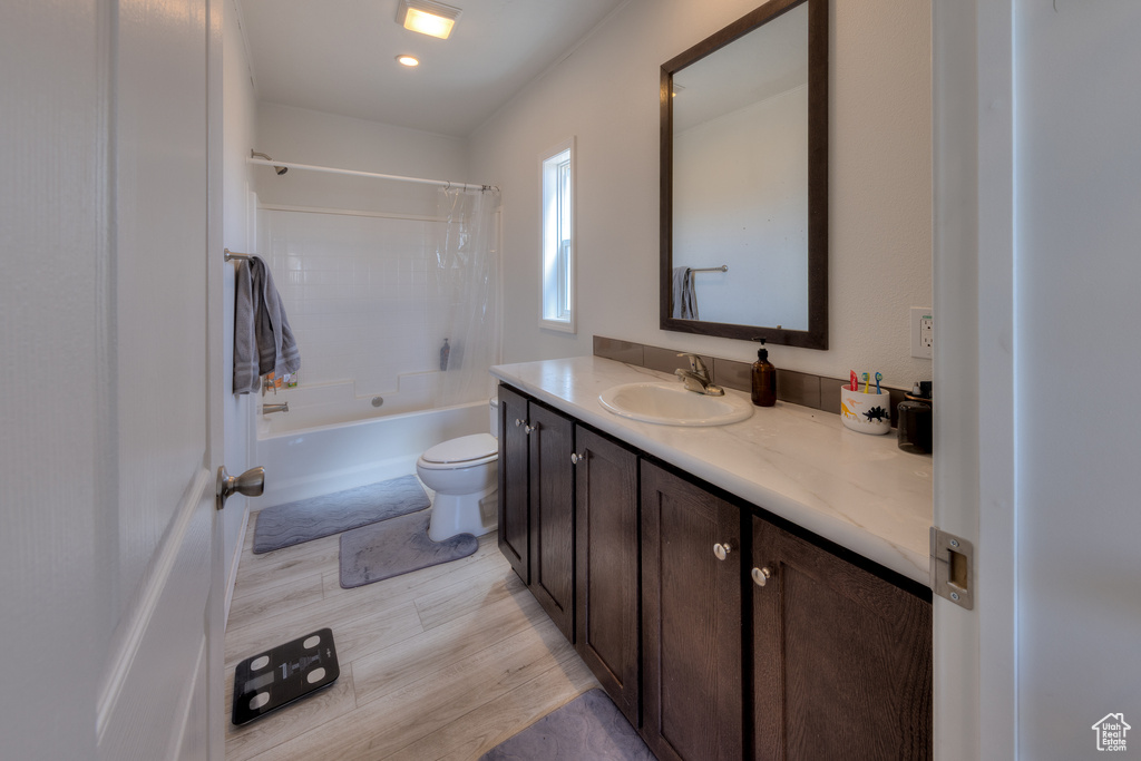 Bathroom featuring shower / tub combo with curtain, wood finished floors, toilet, and vanity
