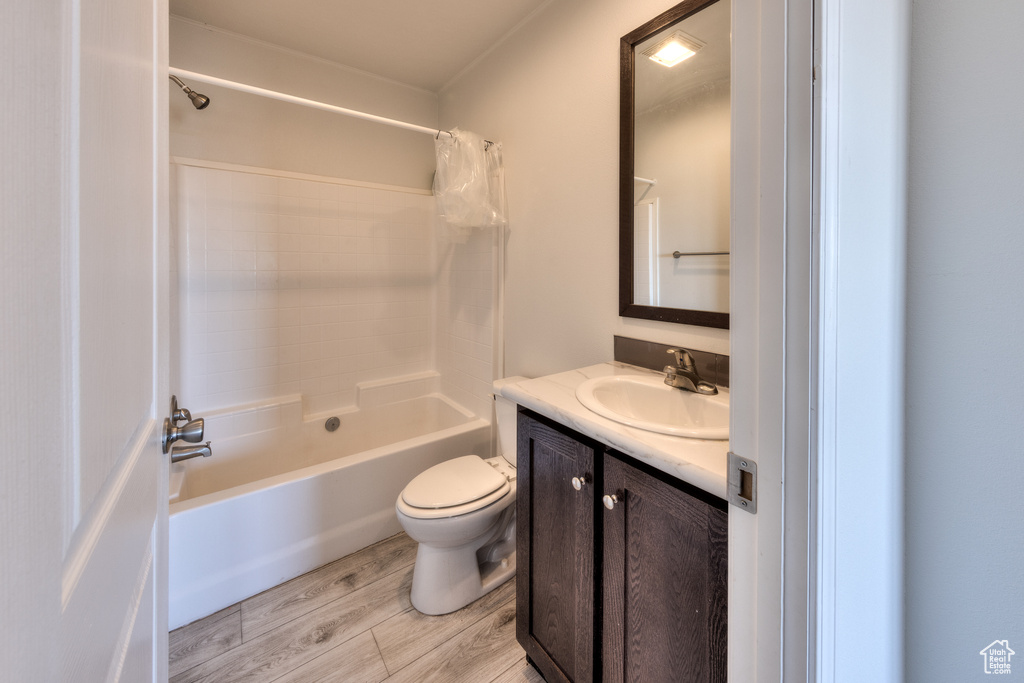 Full bath featuring shower / tub combo with curtain, wood finished floors, toilet, and vanity
