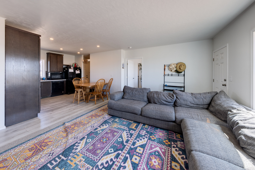 Living room with light wood-style flooring and recessed lighting