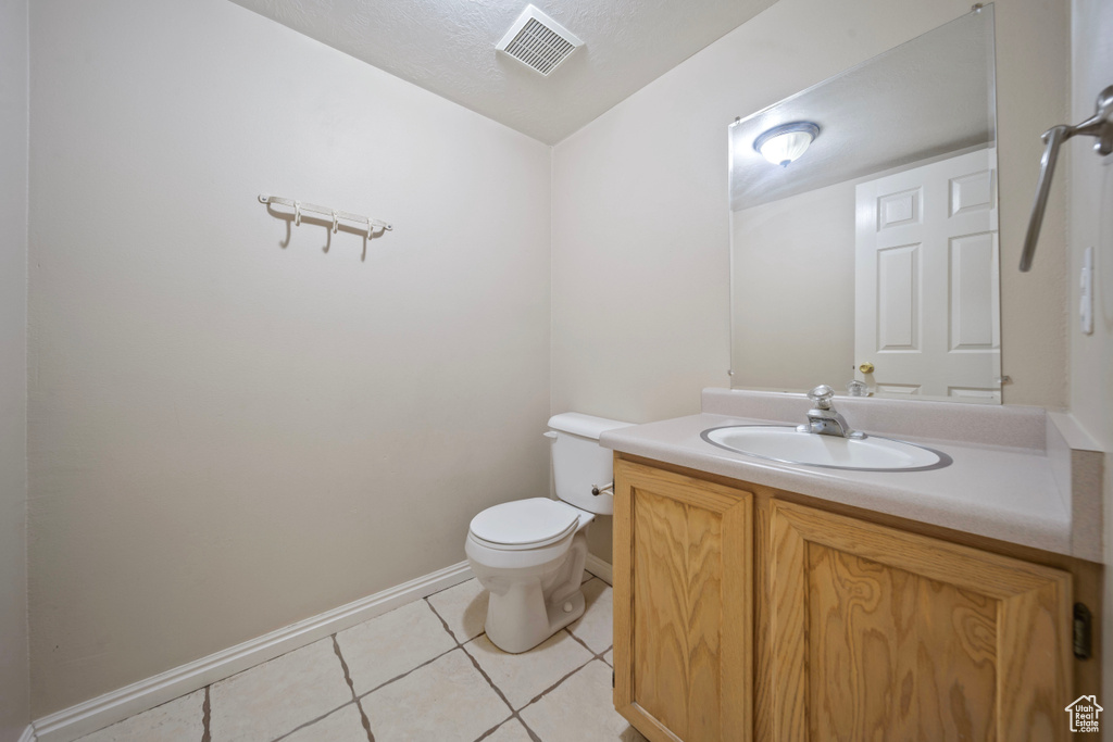 Bathroom featuring visible vents, vanity, toilet, baseboards, and tile patterned floors