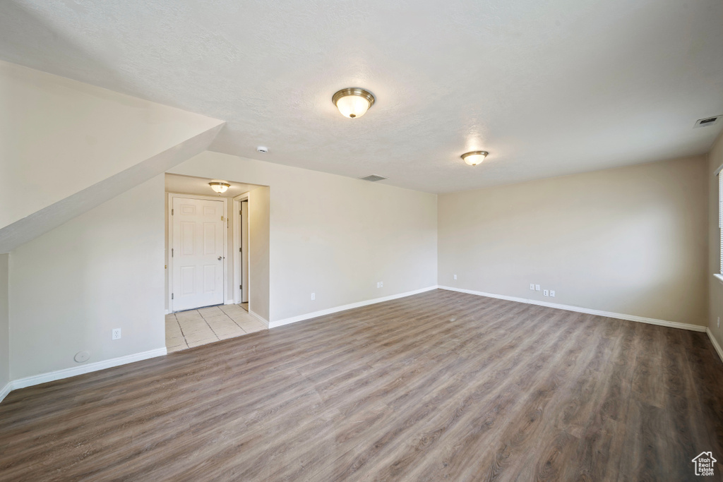 Interior space featuring baseboards, a textured ceiling, wood finished floors, and visible vents