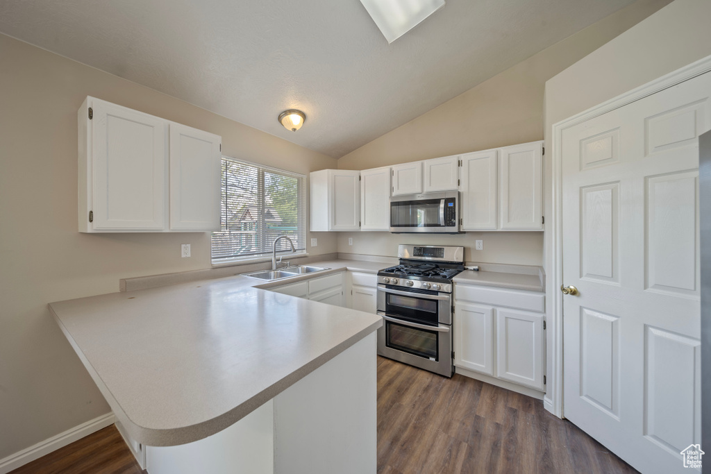 Kitchen featuring a sink, white cabinetry, a peninsula, and stainless steel appliances