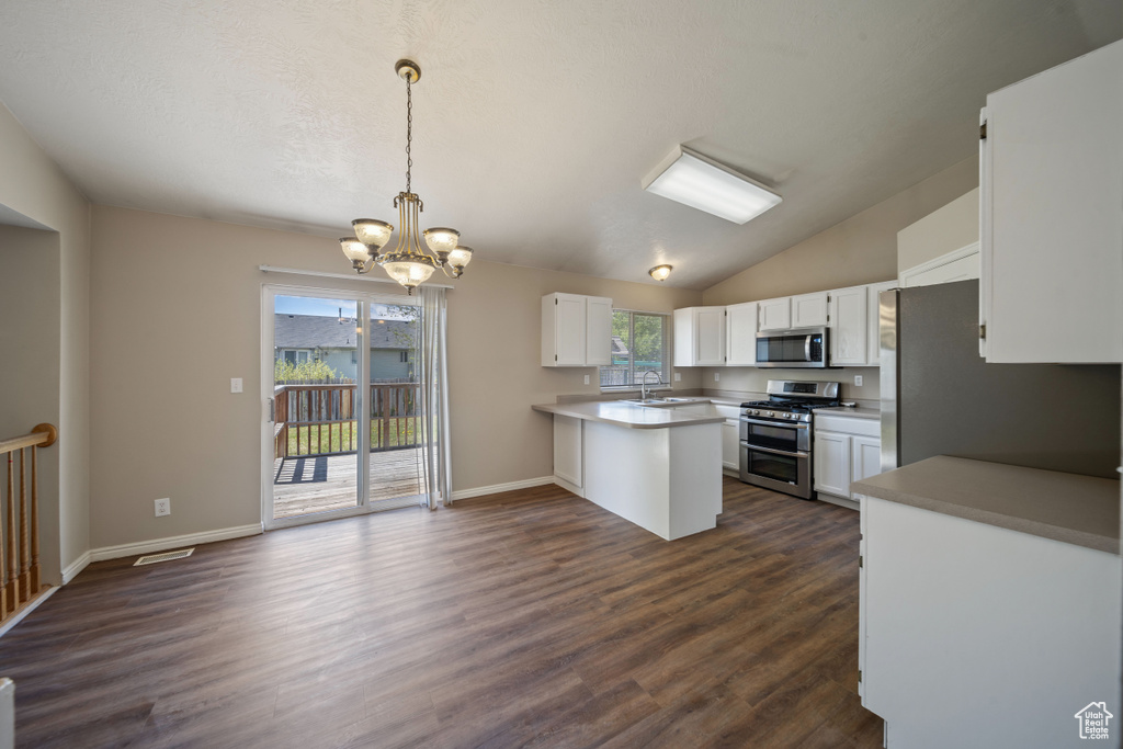 Kitchen featuring a notable chandelier, a sink, stainless steel appliances, white cabinetry, and a peninsula