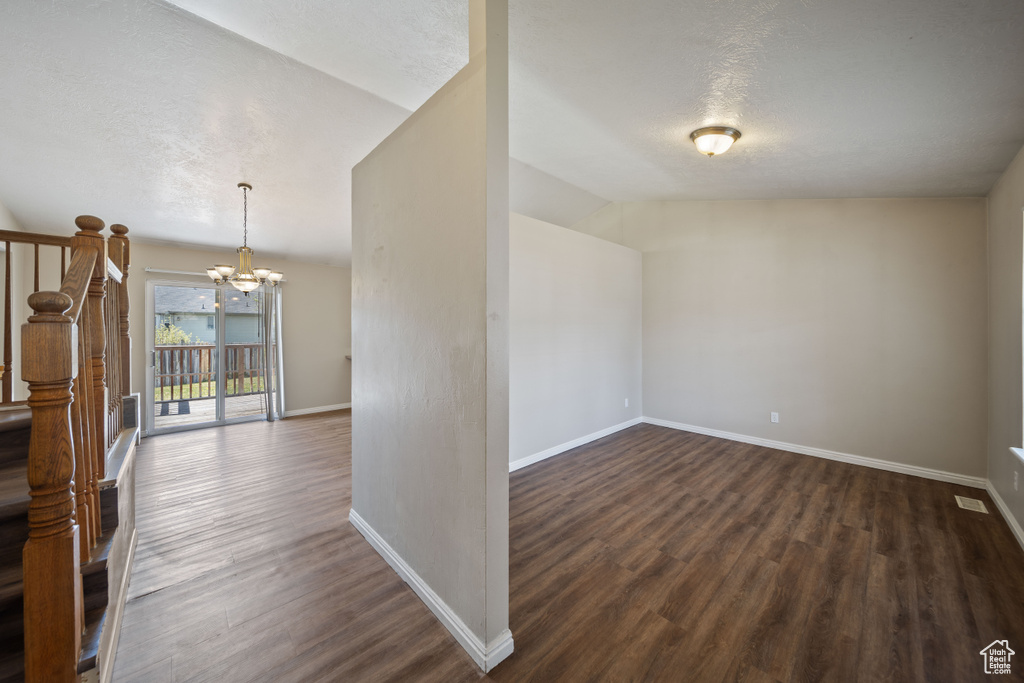 Interior space featuring baseboards, a textured ceiling, dark wood finished floors, and a notable chandelier