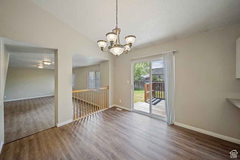 Unfurnished dining area featuring baseboards, wood finished floors, and a chandelier