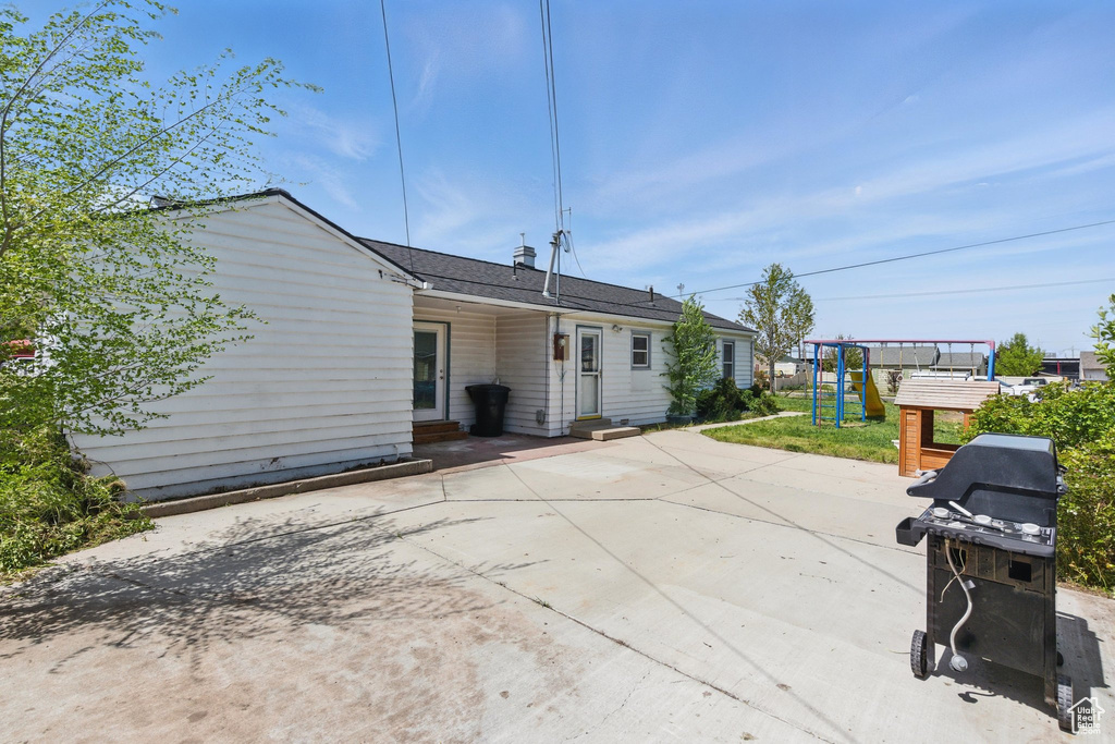 Rear view of house with a playground, entry steps, and a patio area