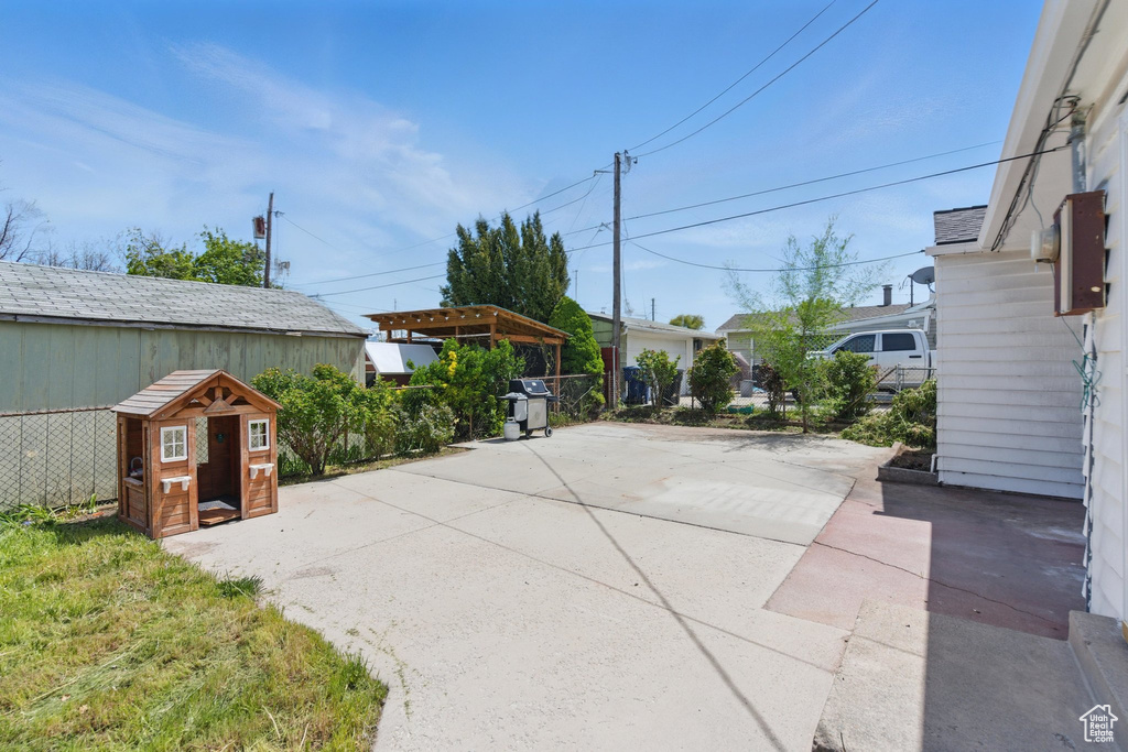 View of patio featuring fence, area for grilling, a pergola, and an outbuilding