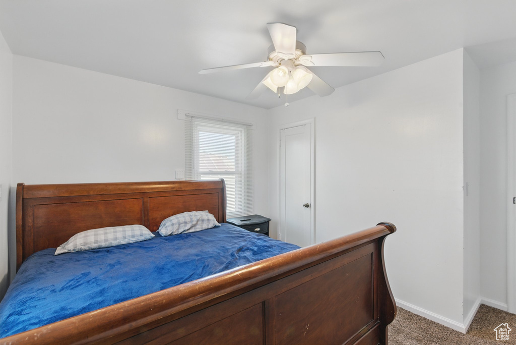 Carpeted bedroom with a ceiling fan and baseboards