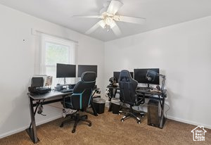Carpeted office with baseboards and a ceiling fan