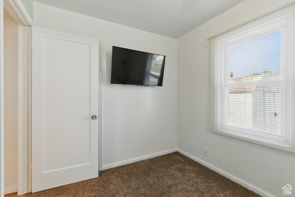 Empty room featuring dark carpet and baseboards