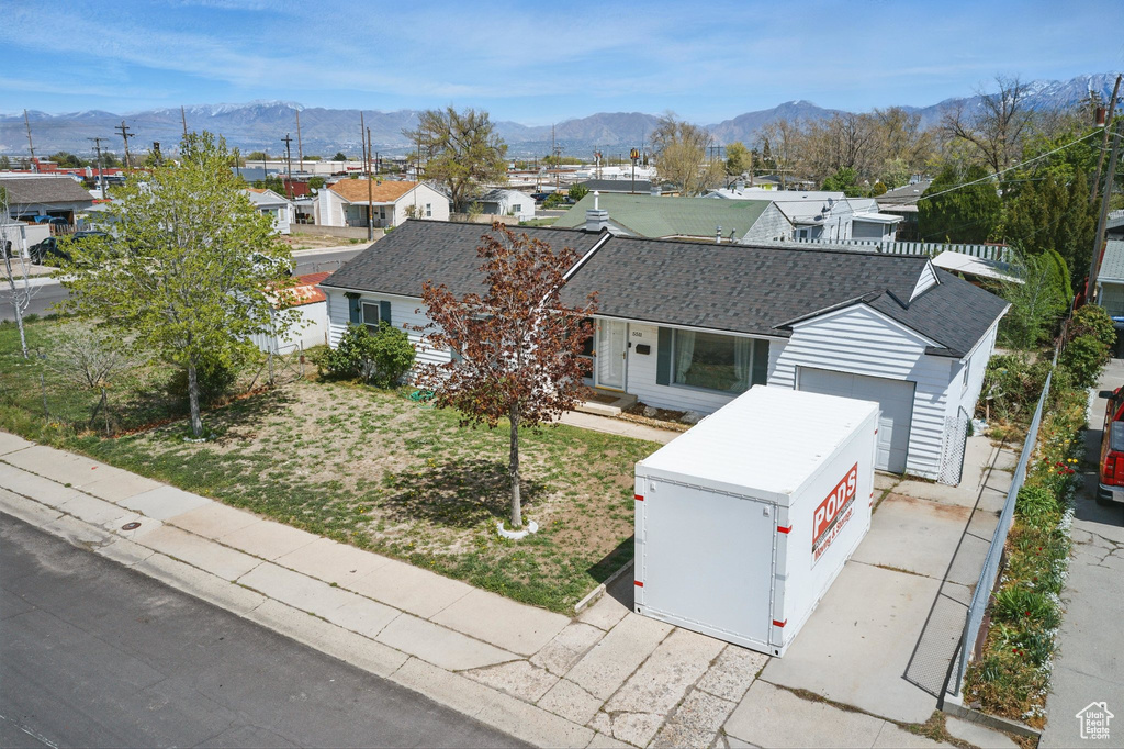 View of front facade with a garage, a mountain view, a shingled roof, and a residential view